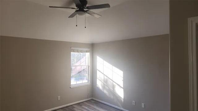 an empty room with windows and fan