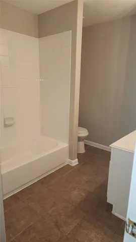 a bathroom with a granite countertop toilet and a tub