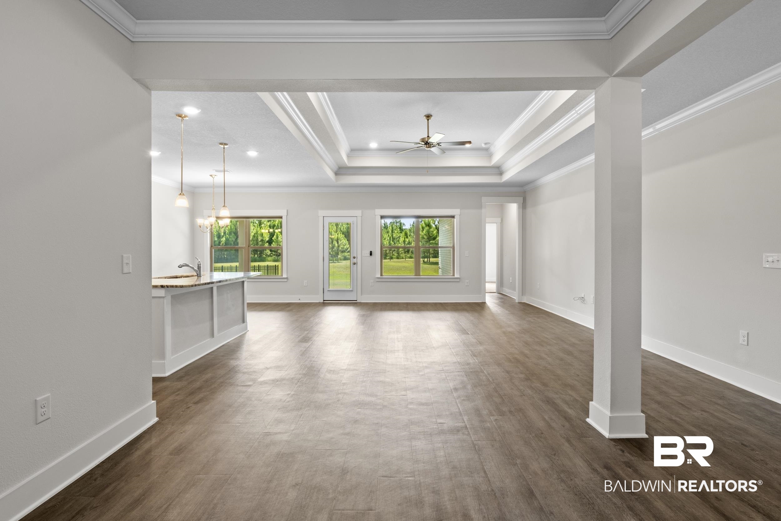 9868 Lakeview Drive Foley, AL 36535 - Photo 13 of 30 Unfurnished living room with crown molding, a tray ceiling, ceiling fan with notable chandelier, and dark hardwood / wood-style floors