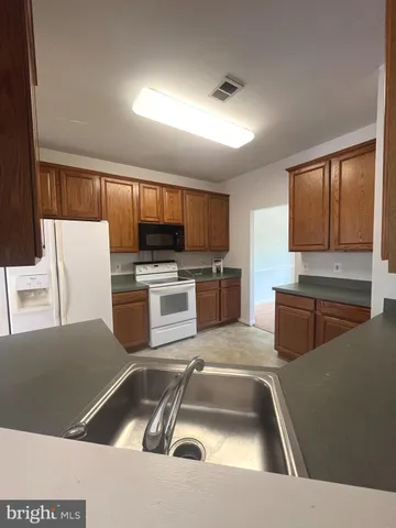 a kitchen that has a sink a counter top space stainless steel appliances and cabinets
