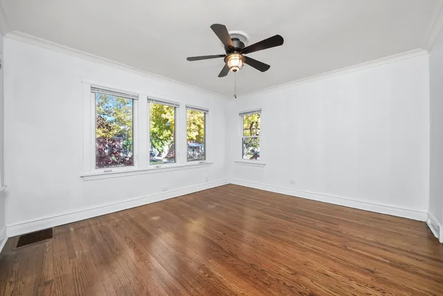 a view of empty room with wooden floor and ceiling fan