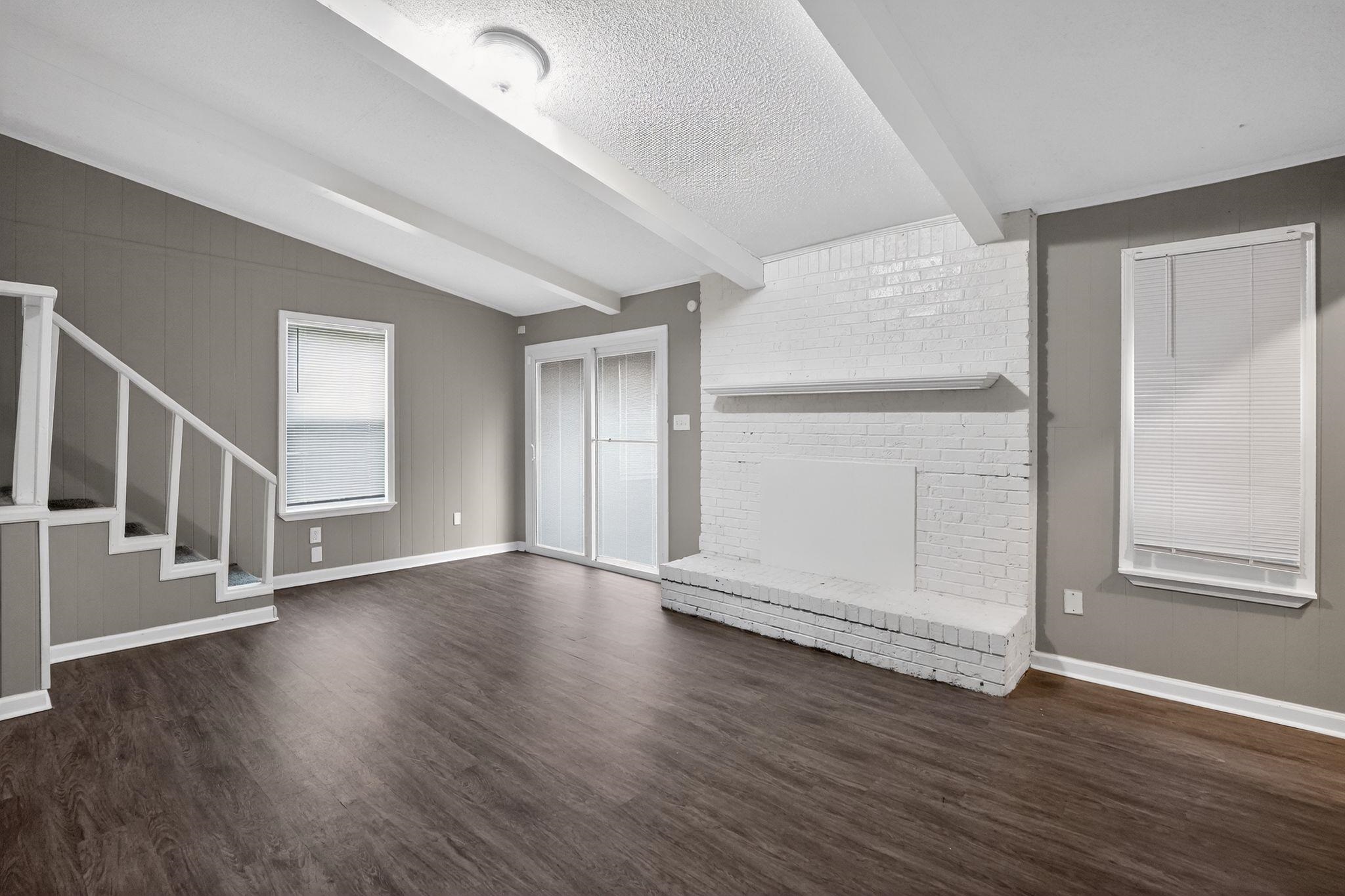 3603 England Street Memphis, TN 38127 - Photo 22 of 36 Unfurnished living room featuring dark wood-style flooring, a fireplace, and beam ceiling