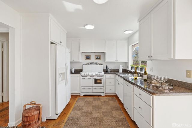 a kitchen with white cabinets sink and stove