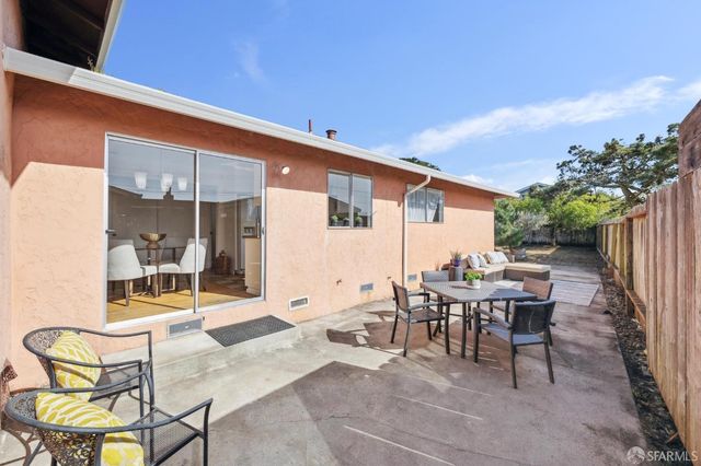 a patio with table and chairs and potted plants
