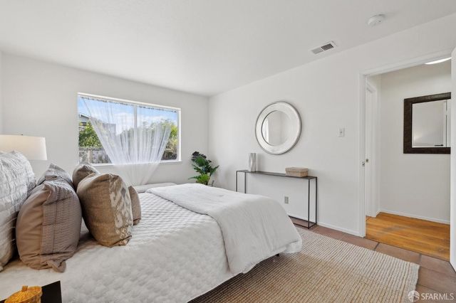 a bedroom with a bed a mirror and windows