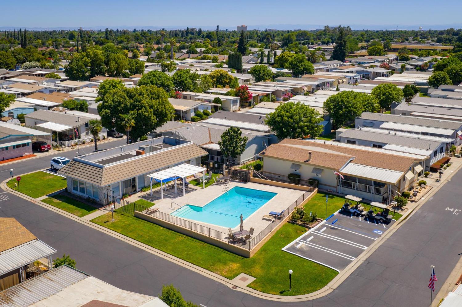 1200 South Carpenter Road, Unit 4 Modesto, CA 95351 - Photo 28 of 31 Community swimming pool with surrounding fence, adjacent shaded patio area, and nearby parking spaces