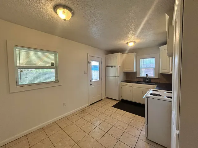 a kitchen with granite countertop a refrigerator and a stove top oven