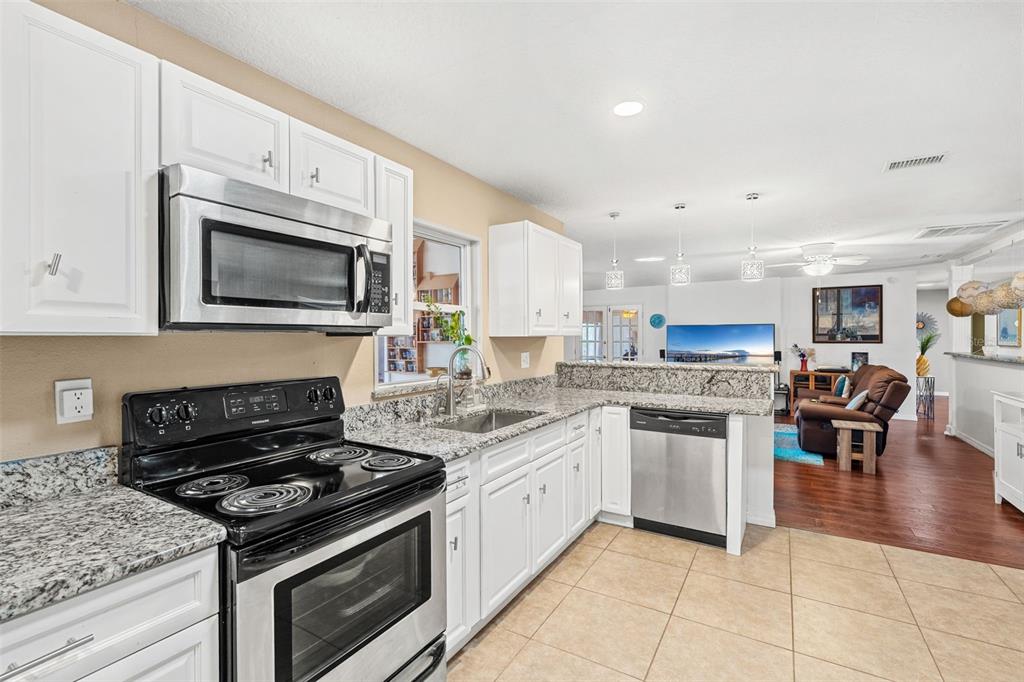1702 Elaine Avenue Altamonte Springs, FL 32701 - Photo 15 of 39 a kitchen with stainless steel appliances granite countertop a stove top oven a sink dishwasher and a stove