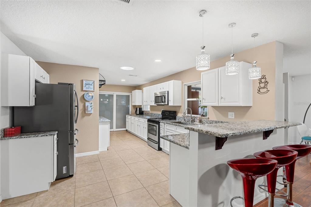 1702 Elaine Avenue Altamonte Springs, FL 32701 - Photo 17 of 39 a kitchen with stainless steel appliances kitchen island granite countertop a refrigerator and a stove top oven