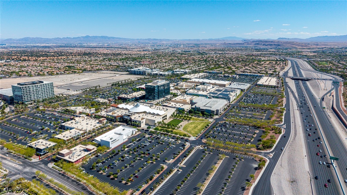 2153 Quarry Ridge Street, Unit 103 Las Vegas, NV 89117 - Photo 40 of 42 An aerial perspective reveals a vibrant commercial hub adjacent to a bustling highway, set against a distant mountain backdrop.