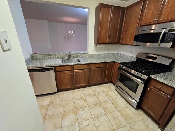 a kitchen with granite countertop a refrigerator a stove top oven a sink and dishwasher