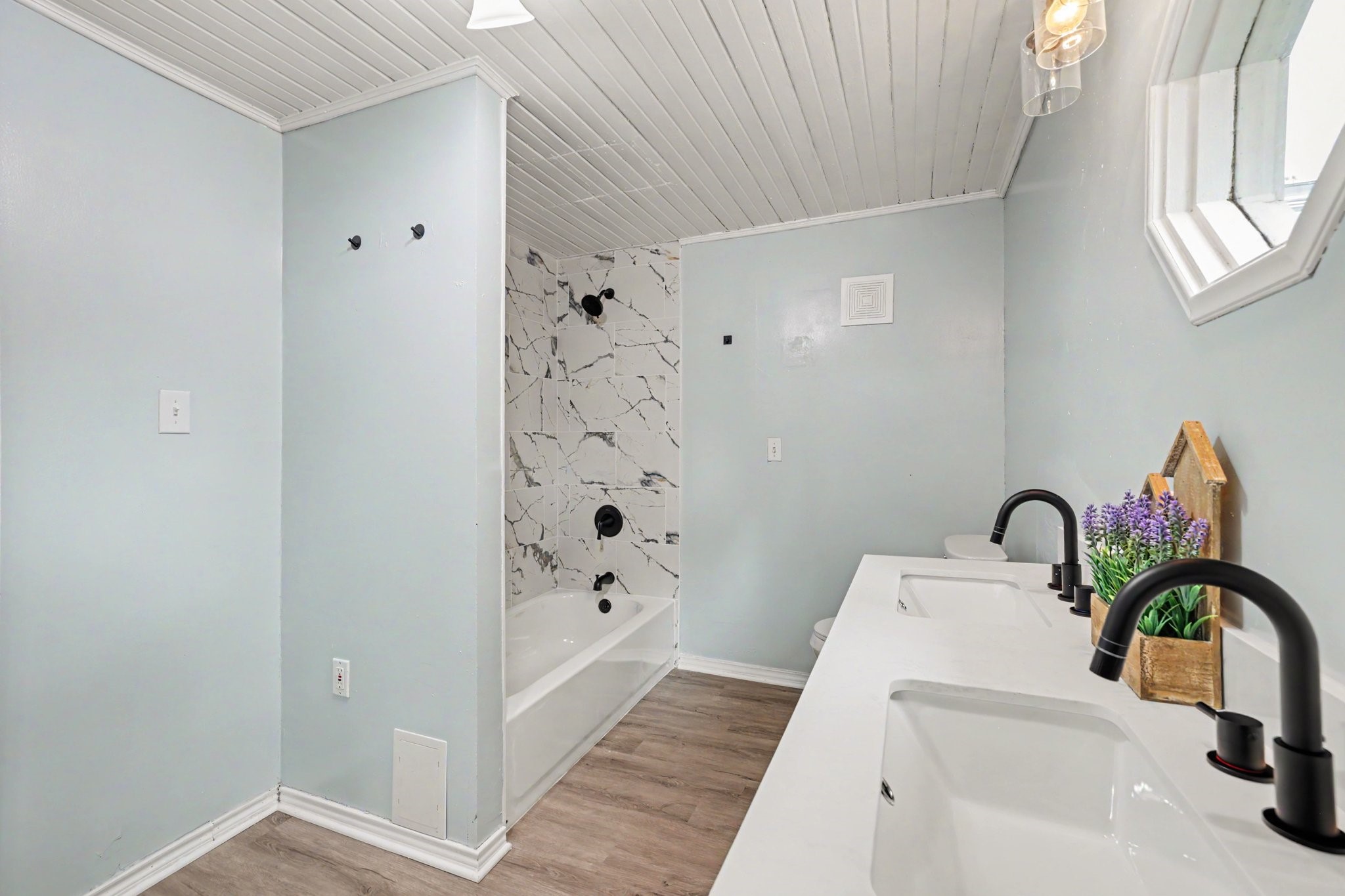 31730 Waller Tomball Road Waller, TX 77484 - Photo 29 of 50 This bathroom features a modern design with a dual-sink vanity and a marble-tiled shower area. The light blue walls and luxury vinyl flooring create a fresh, clean atmosphere.