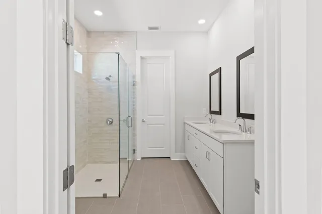 a bathroom with a double vanity sink mirror and shower