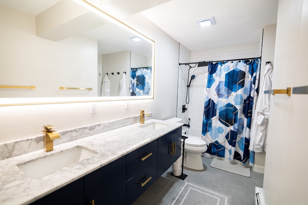2 Turning Mill Lane, Unit 1 Quincy, MA 02169 - Photo 12 of 15 a bathroom with a granite countertop sink mirror and a shower