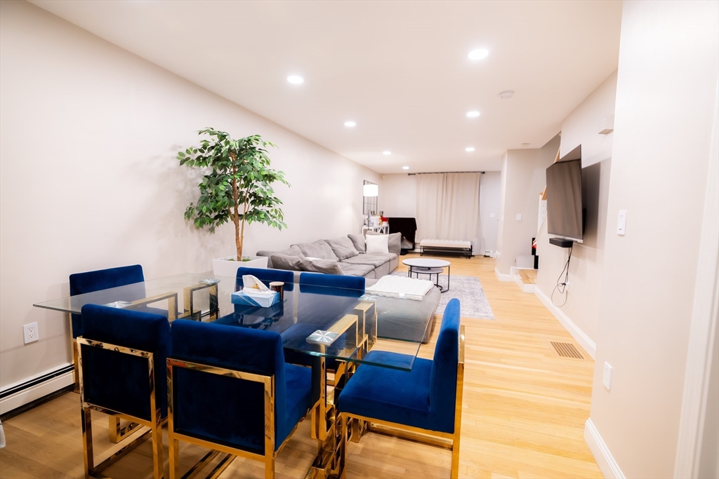 2 Turning Mill Lane, Unit 1 Quincy, MA 02169 - Photo 3 of 15 a living room with furniture a dining table and chairs with potted plants