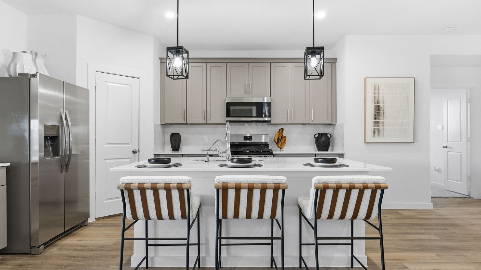 a kitchen with stainless steel appliances granite countertop a dining table chairs refrigerator and microwave