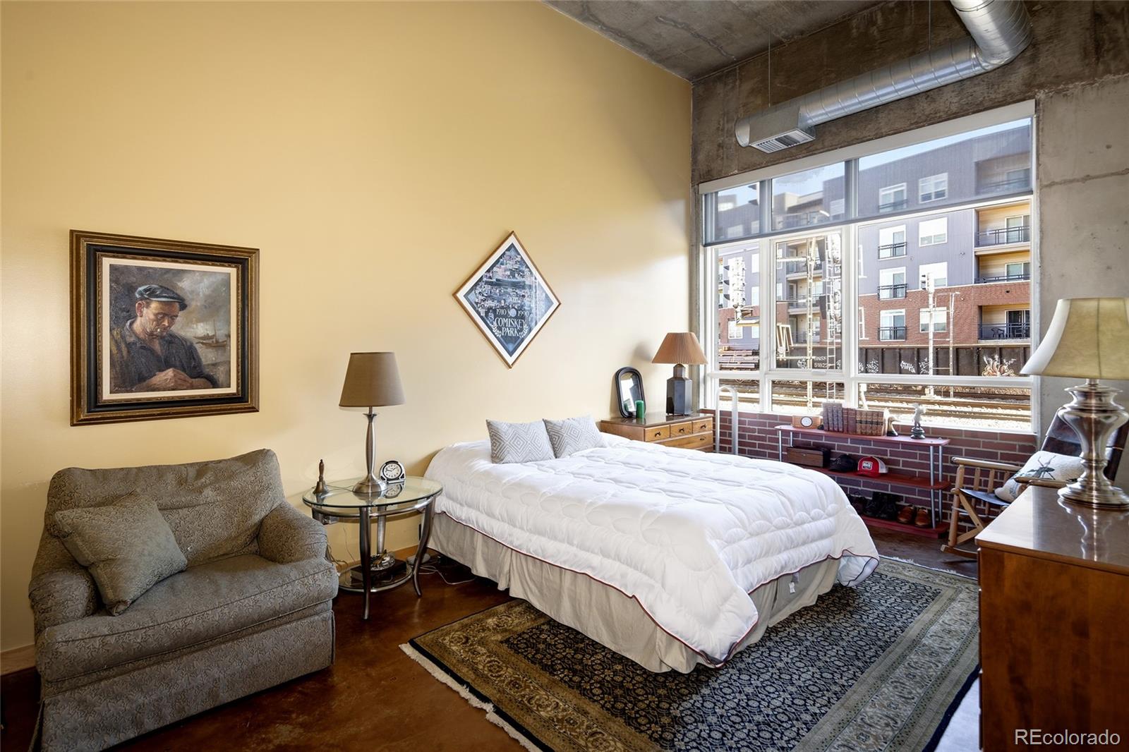 2000 Little Raven Street, Unit 102 Denver, CO 80202 - Photo 3 of 36 a bedroom with a bed a couch and a large window