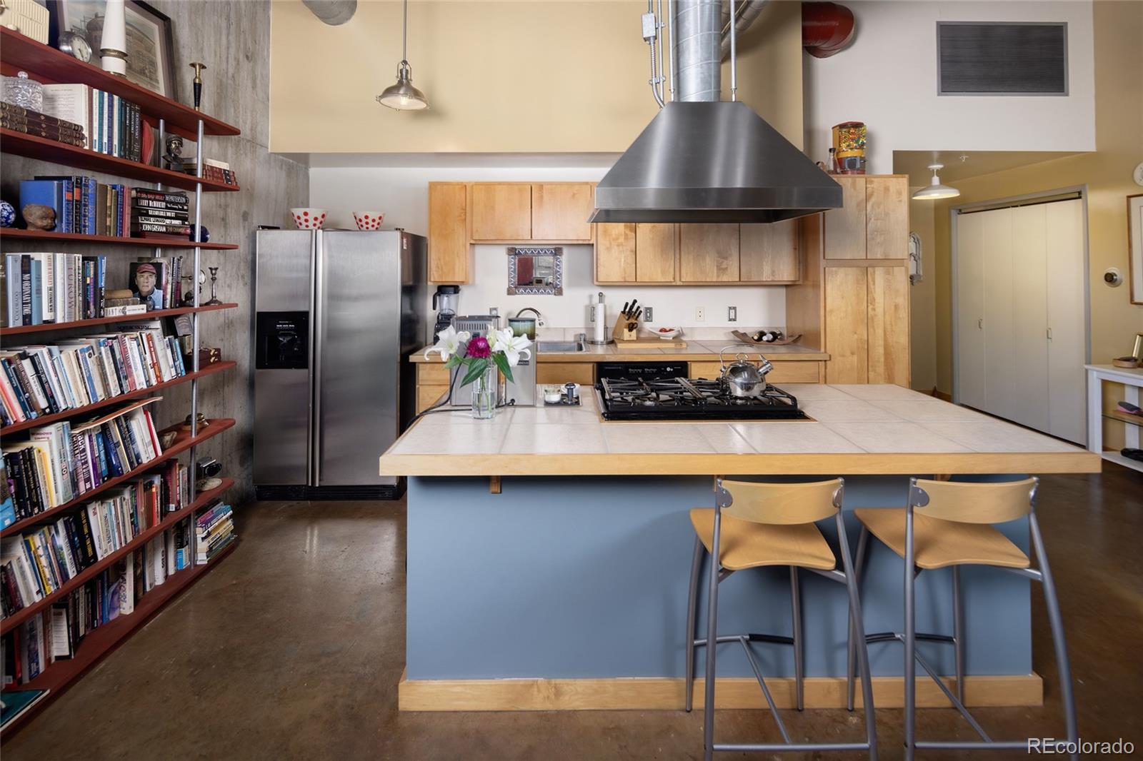 2000 Little Raven Street, Unit 102 Denver, CO 80202 - Photo 6 of 36 a kitchen with stainless steel appliances a table chairs and a book shelf
