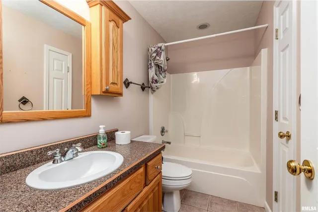 a bathroom with a granite countertop sink toilet a mirror and shower