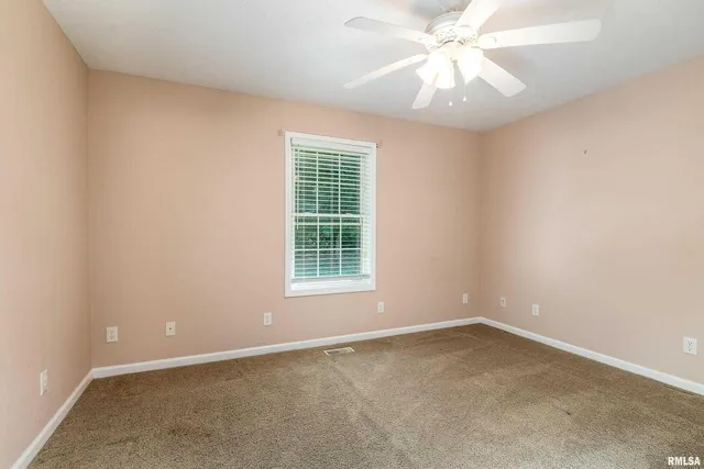 an empty room with a window and a fan