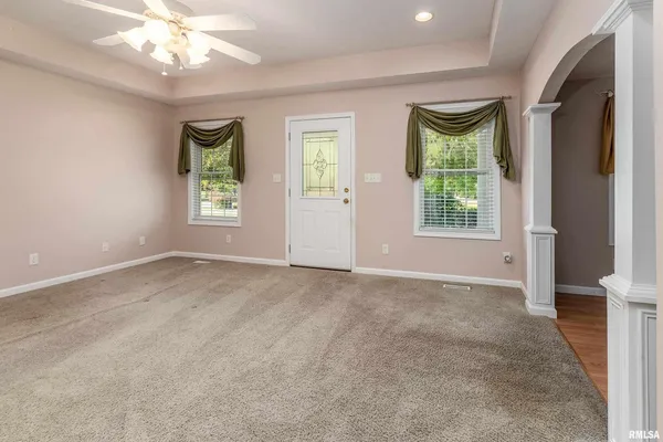 an empty room with windows and chandelier fan