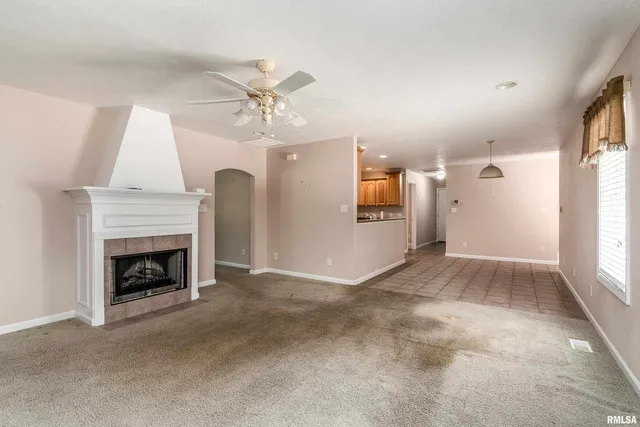 a view of a livingroom with a fireplace a ceiling fan and window