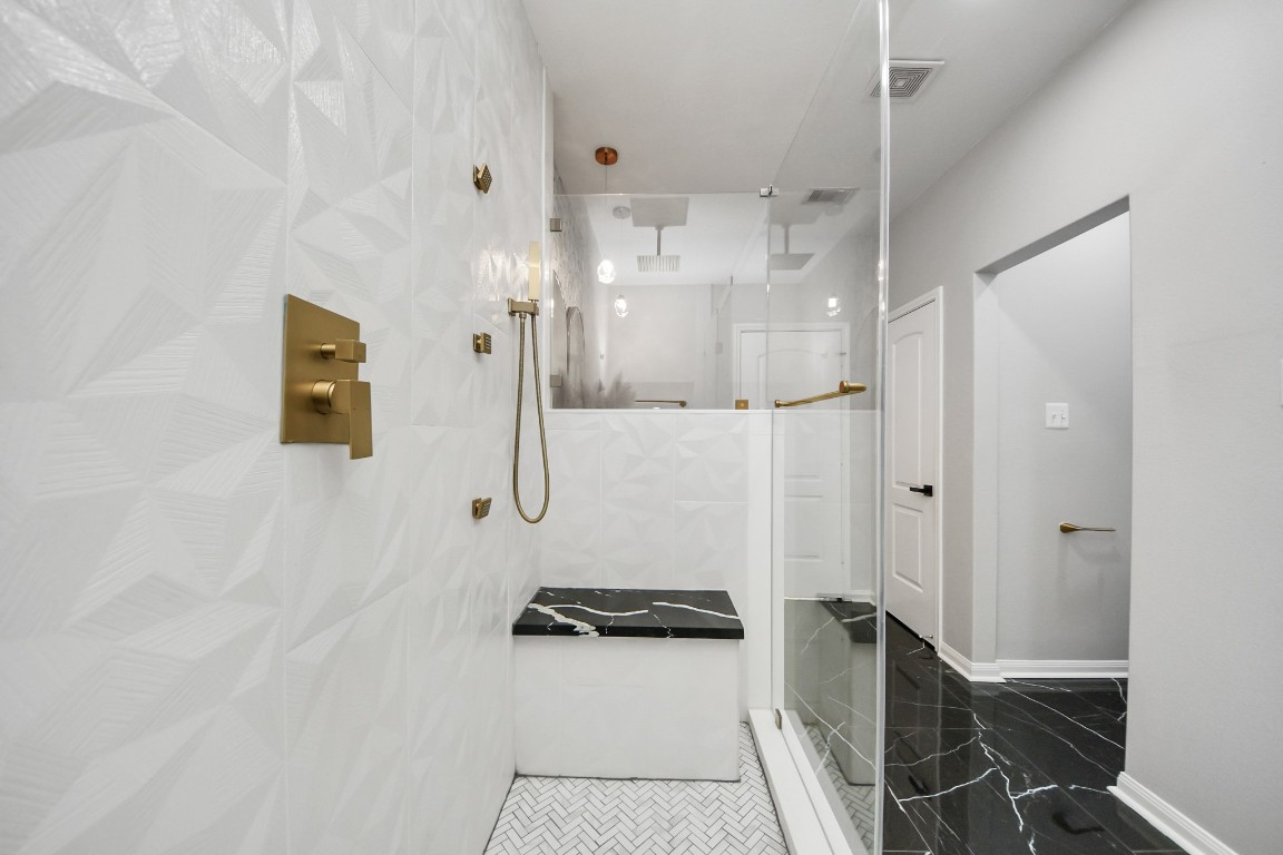 6931 Primrose Road Baytown, TX 77521 - Photo 25 of 50 Elegant walk-in shower with textured wall tile, gold fixtures, and built-in bench seating.