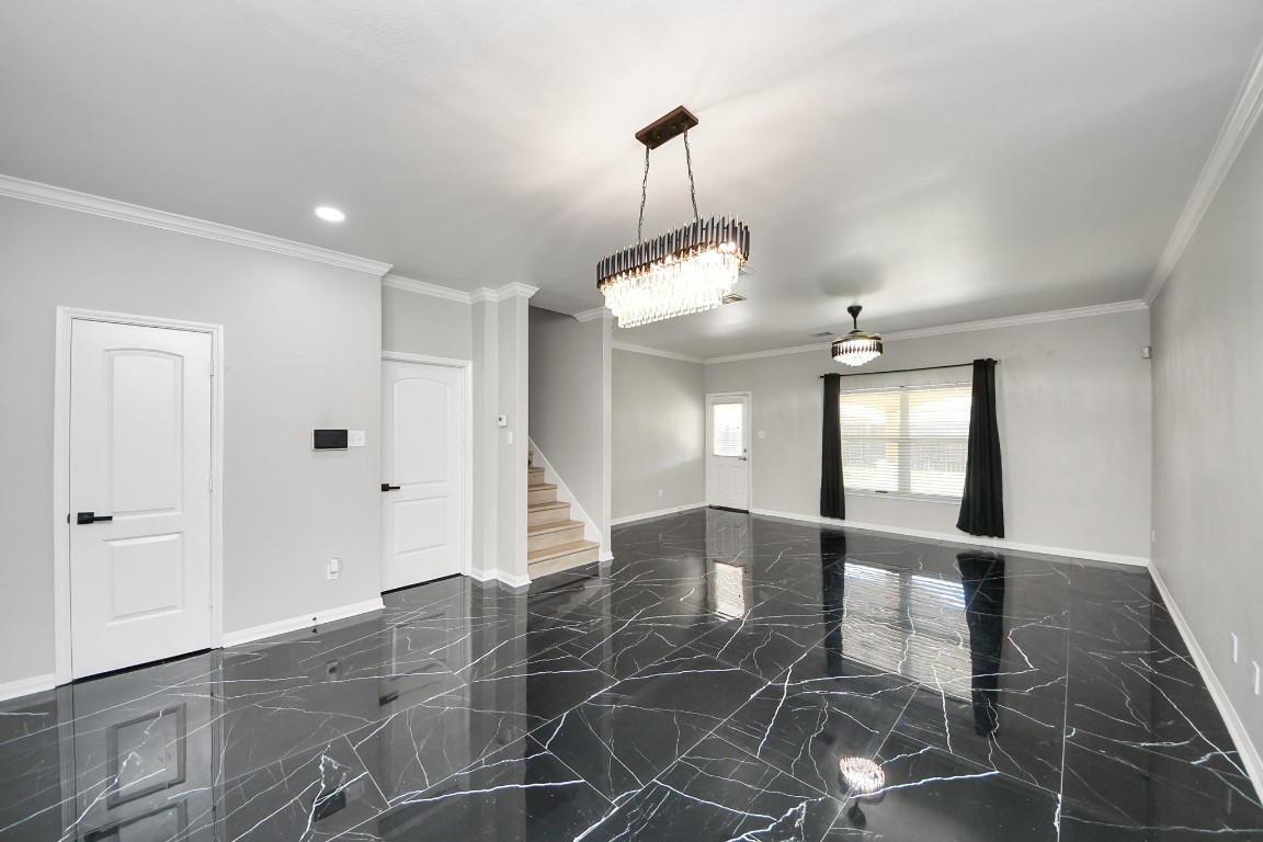 6931 Primrose Road Baytown, TX 77521 - Photo 27 of 50 Elegant open-concept living and dining area featuring glossy marble-look tile floors, crown molding, and designer chandeliers with abundant natural light.