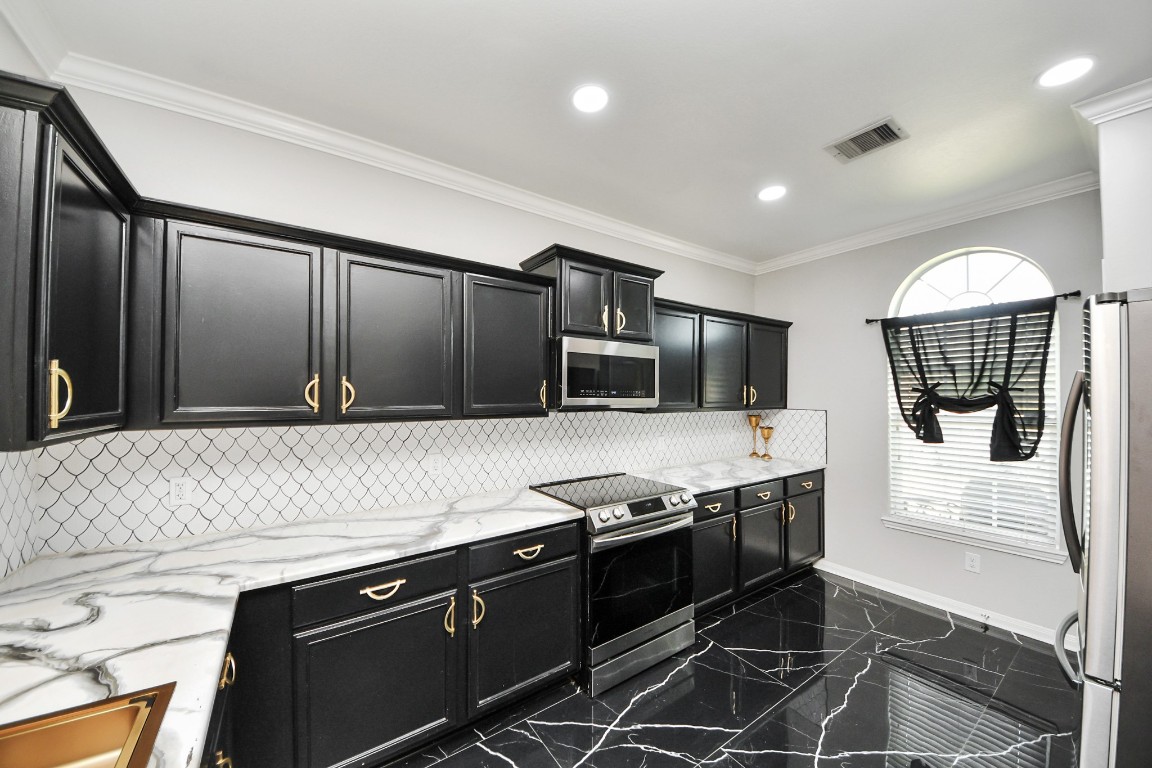 6931 Primrose Road Baytown, TX 77521 - Photo 8 of 50 Kitchen offers ample cabinetry, expansive marble counter space, stainless steel appliances, and elegant gold accents.