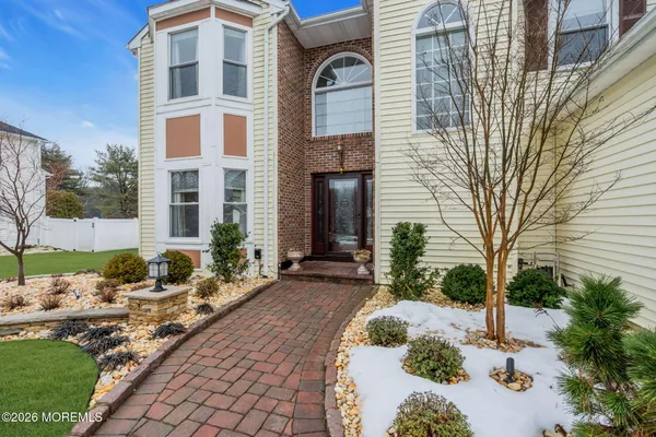 a view of a brick house with a yard and large tree