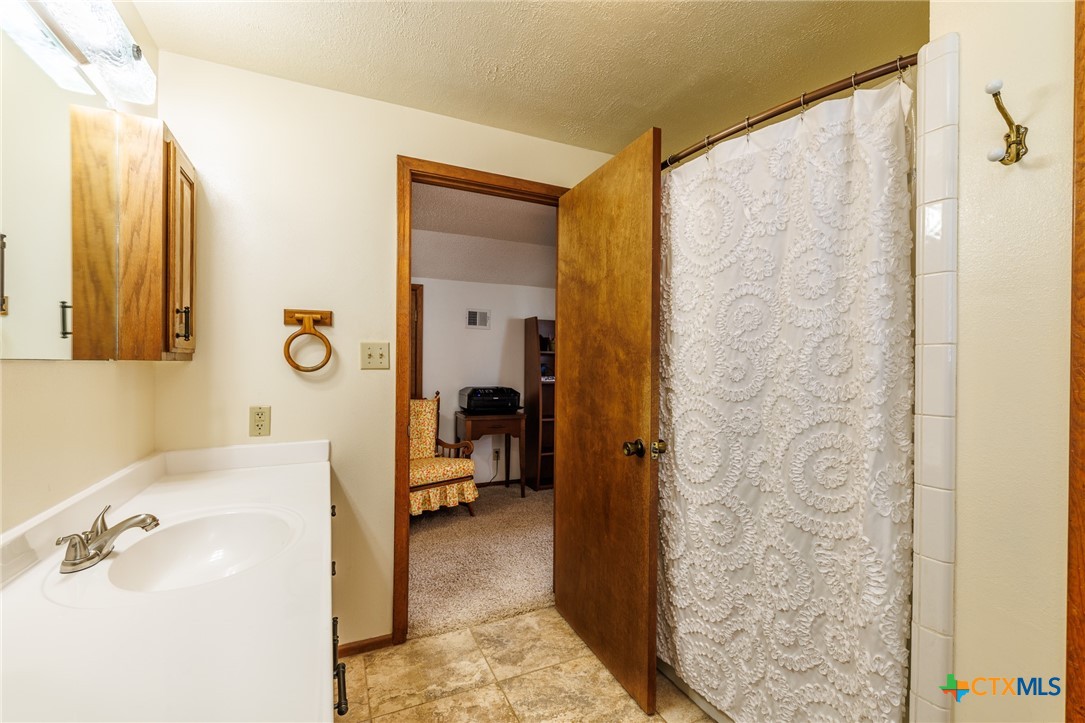 2110 Immenhauser Road Yoakum, TX 77995 - Photo 25 of 39 a bathroom with a sink a mirror and a shower