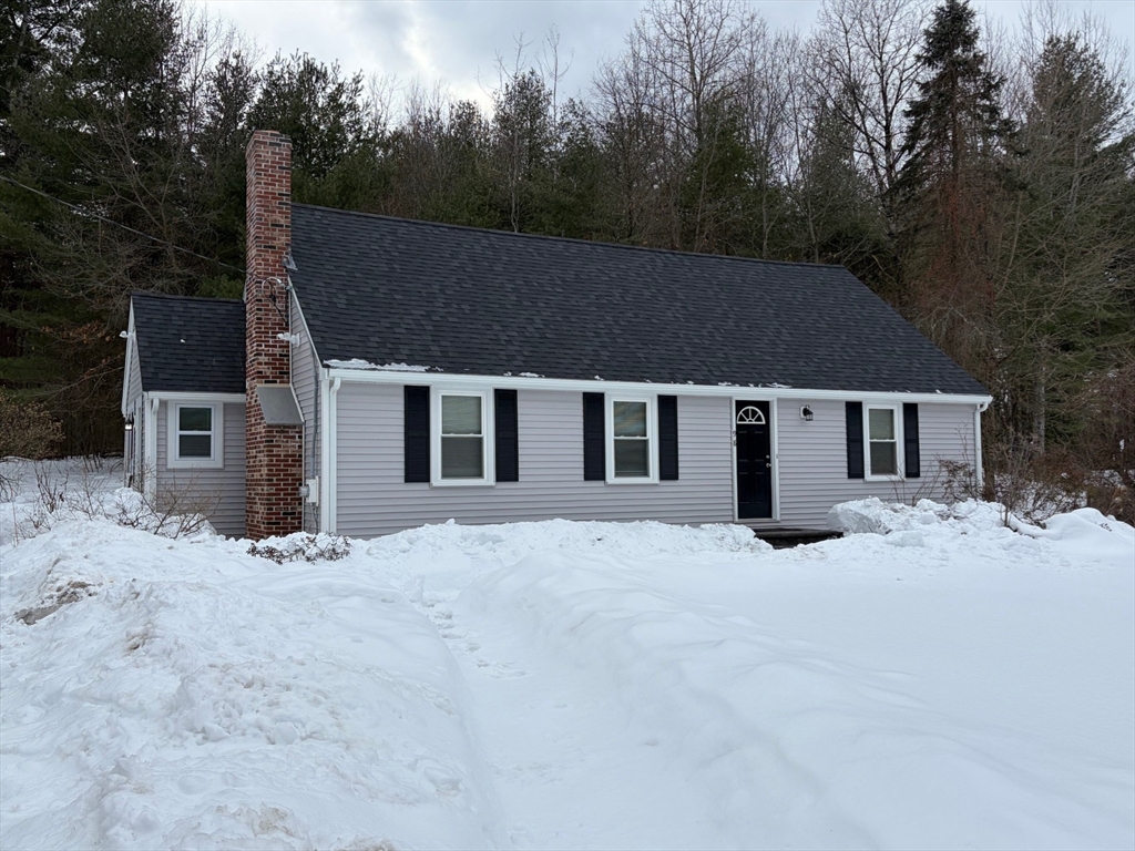 a front view of house with yard and trees in the background