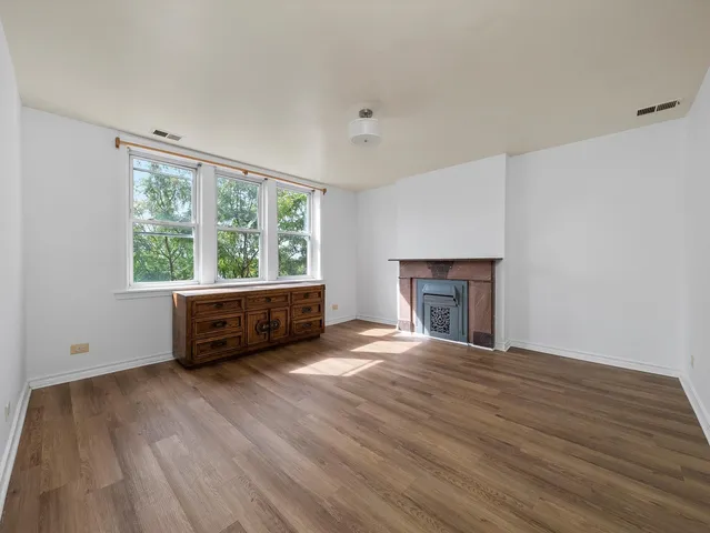 a view of empty room with wooden floor and fireplace