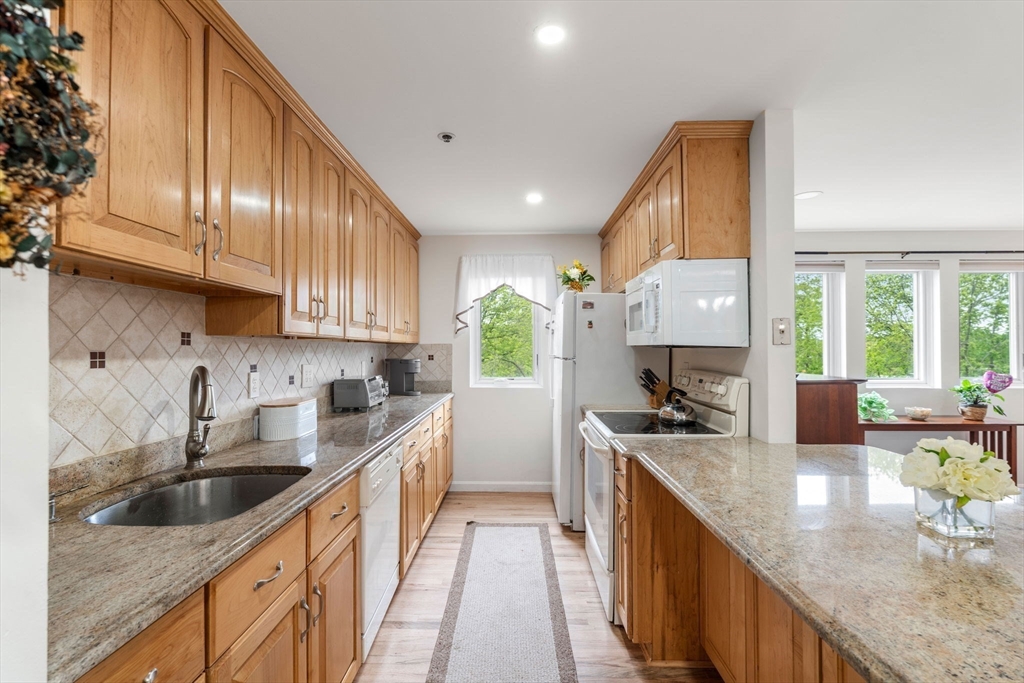 36 Dunham Road, Unit 109 Beverly, MA 01915 - Photo 1 of 22 a kitchen with stainless steel appliances granite countertop a sink a stove and a wooden cabinets