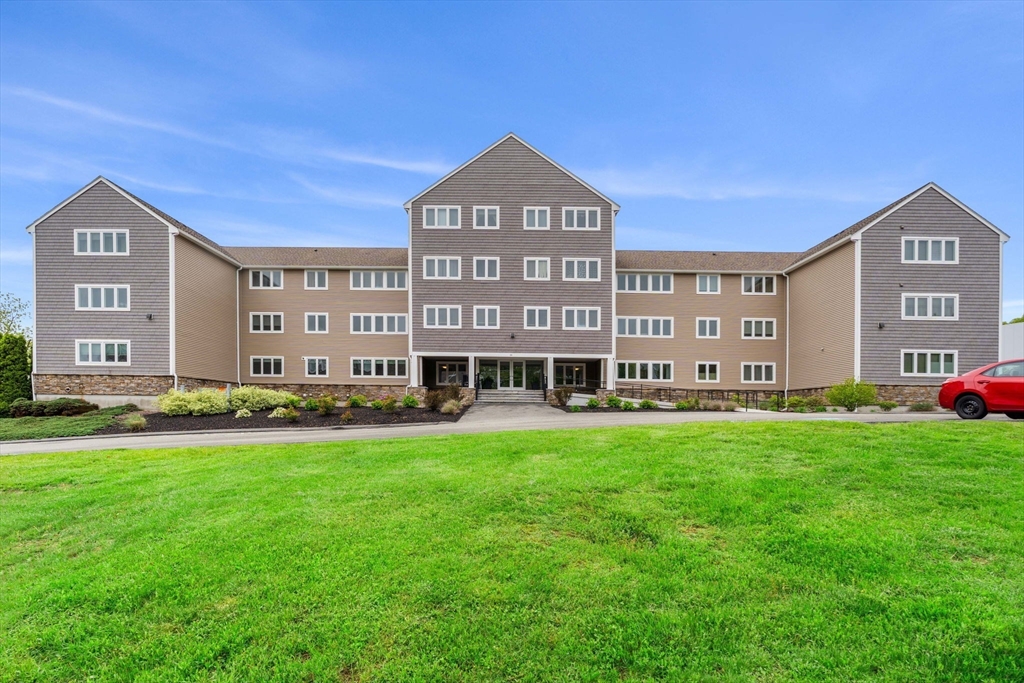 36 Dunham Road, Unit 109 Beverly, MA 01915 - Photo 19 of 22 a view of a big building with a big yard and large trees