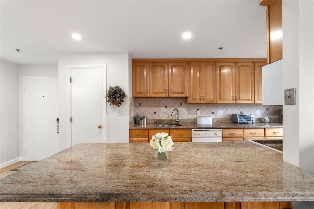 36 Dunham Road, Unit 109 Beverly, MA 01915 - Photo 2 of 22 a kitchen with kitchen island granite countertop a refrigerator and cabinets