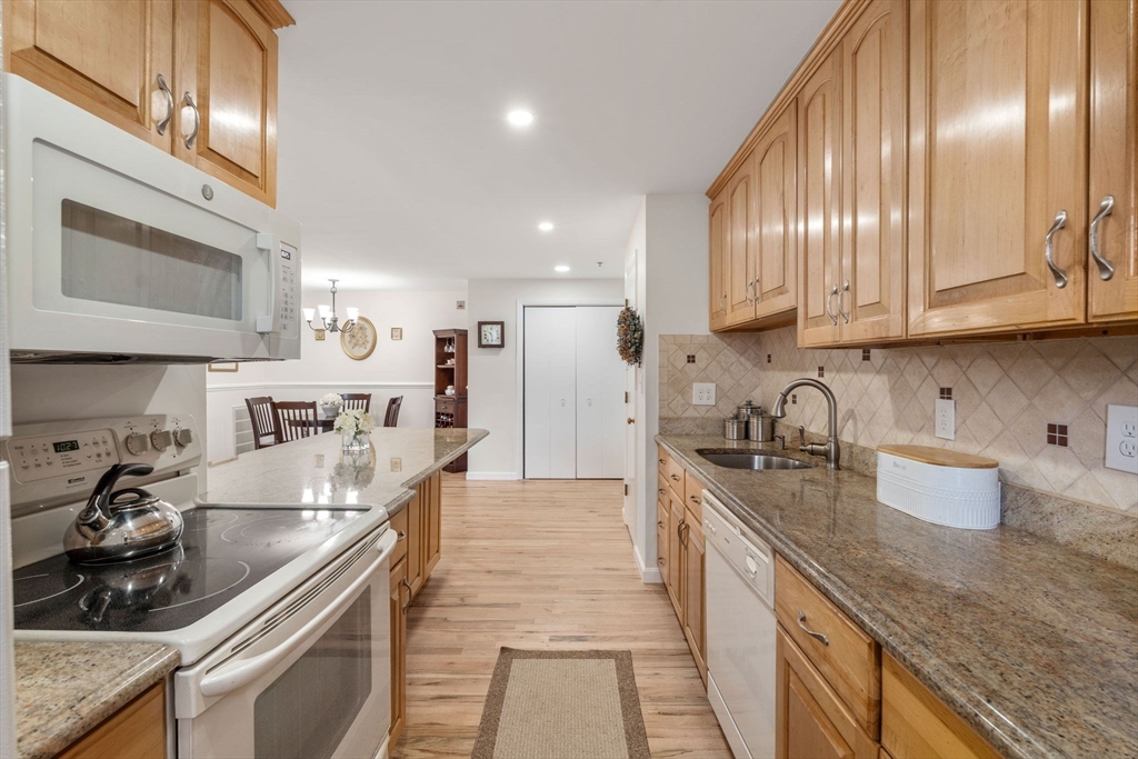 36 Dunham Road, Unit 109 Beverly, MA 01915 - Photo 3 of 22 a large kitchen with stainless steel appliances granite countertop a sink a stove and a wooden cabinets