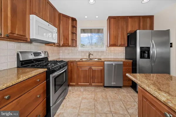 a kitchen with stainless steel appliances granite countertop a stove a sink dishwasher and a refrigerator