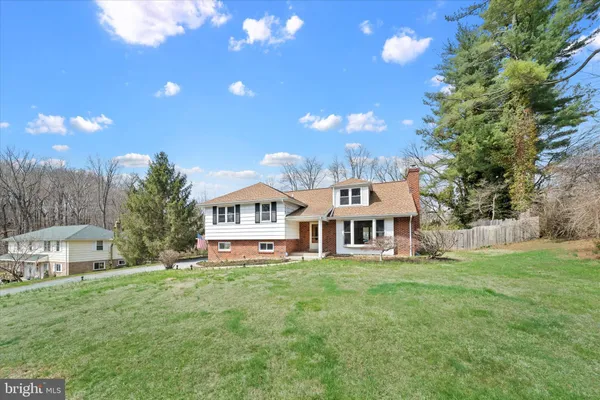 a view of a house with a big yard and large trees