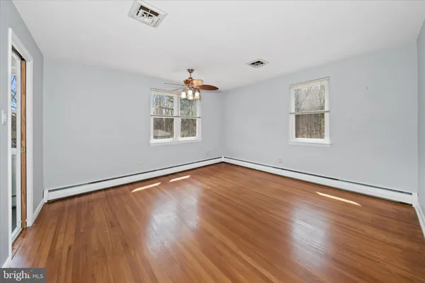 an empty room with wooden floor and windows