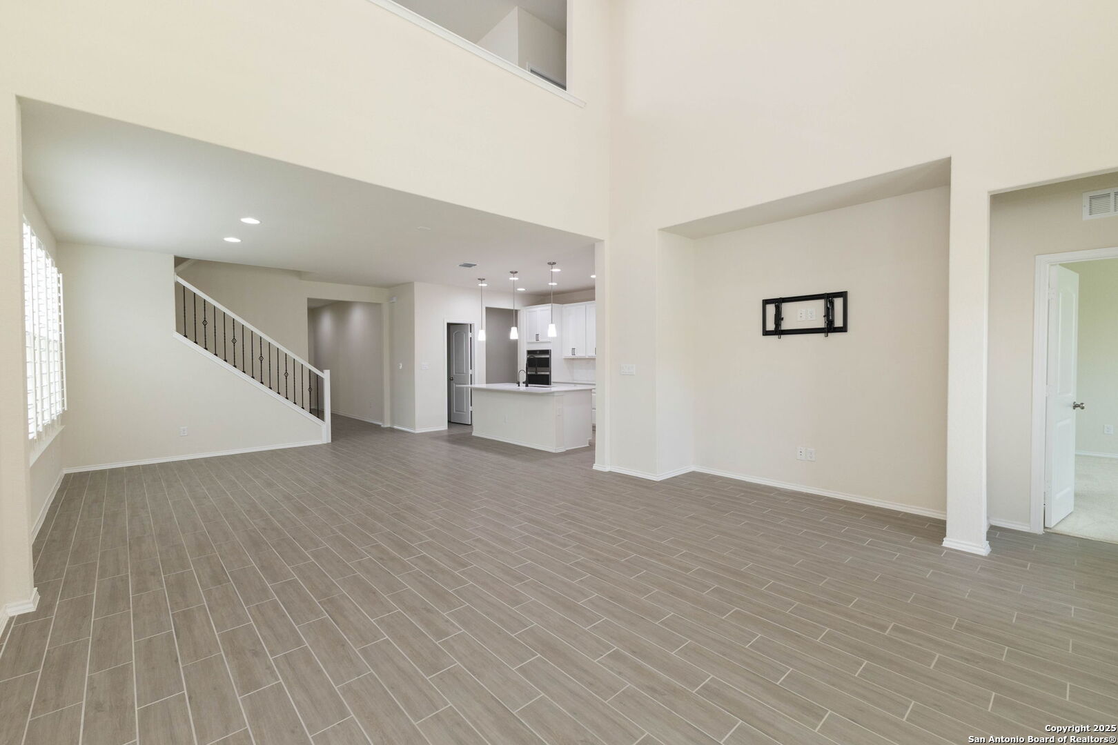 353 Aberdeen Boerne, TX 78015 - Photo 9 of 36 an empty room with wooden floor and a kitchen view