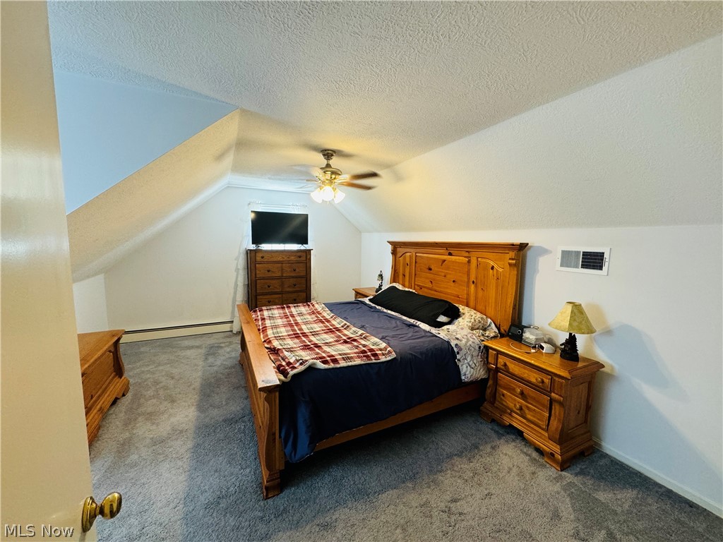 9531 West Ridge Road Elyria, OH 44035 - Photo 16 of 32 Bedroom with a baseboard radiator, ceiling fan, dark colored carpet, a textured ceiling, and lofted ceiling