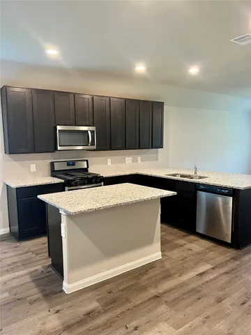 a kitchen with stainless steel appliances granite countertop a stove a sink and a microwave