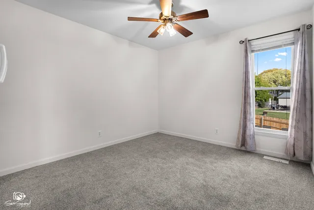an empty room with a window and a fan