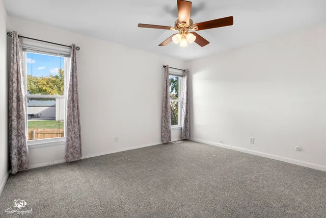 an empty room with windows and fan