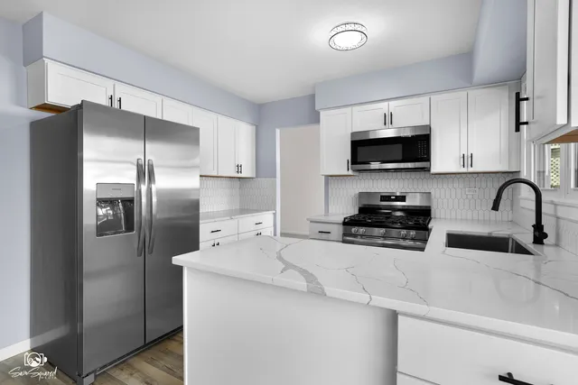 a kitchen with stainless steel appliances a refrigerator a sink a stove a microwave and cabinets