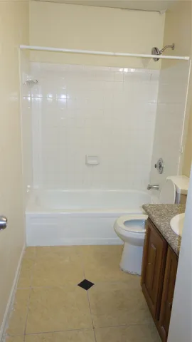a bathroom with a granite countertop bathtub shower sink vanity and toilet