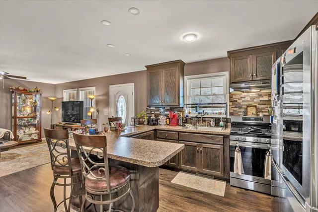 a kitchen with stainless steel appliances a table and chairs in it