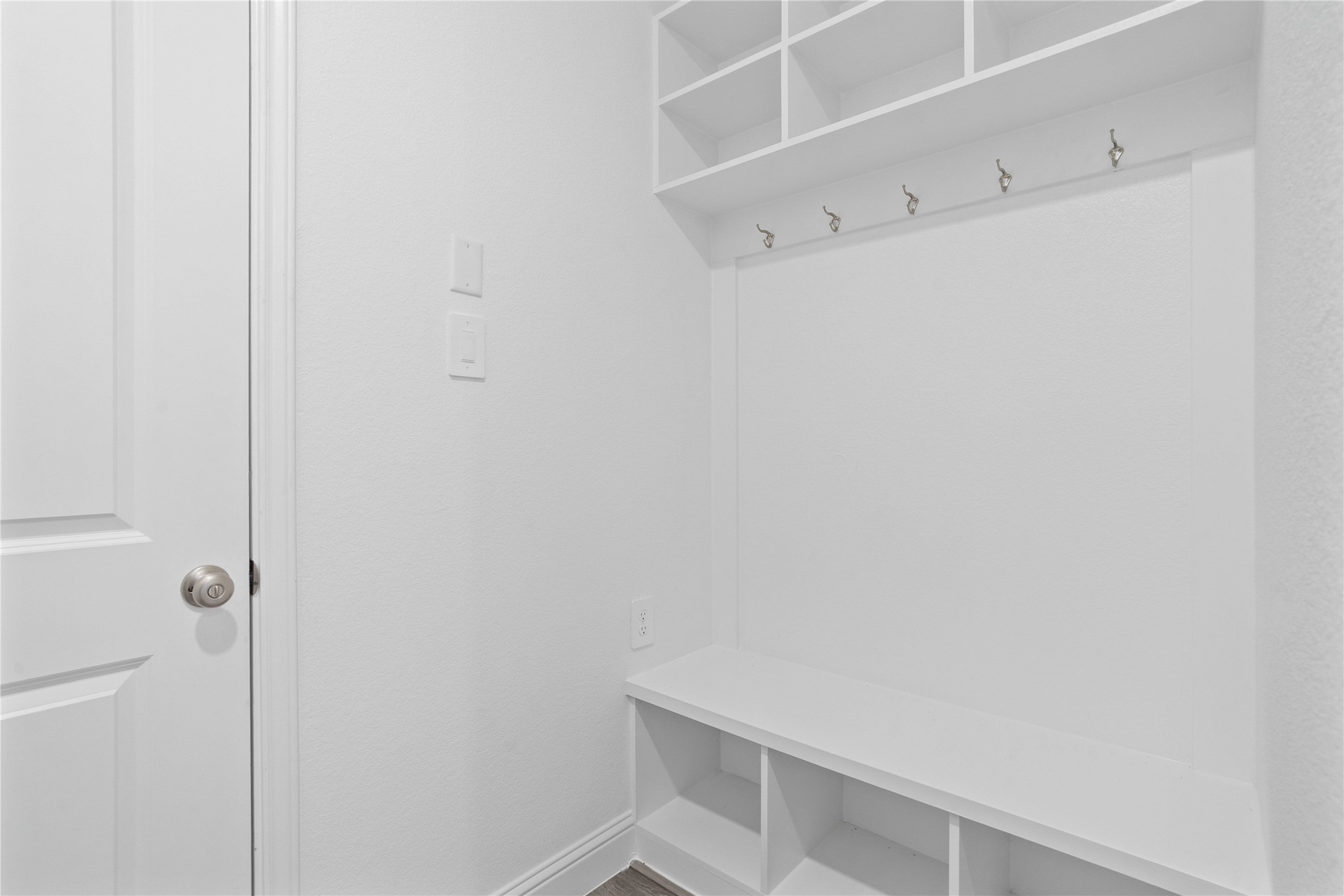 17315 July Moon Lane Conroe, TX 77302 - Photo 31 of 46 Step into this highly functional and stylish mudroom drop zone, an essential feature for a busy household. The space boasts custom-built white cabinetry and shelving, providing generous storage for coats, bags, and shoes. A comfortable built-in bench offers a convenient spot to sit, while three sleek hooks keep outerwear tidy and accessible.