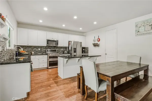 a kitchen with granite countertop a stove a sink a dining table and chairs